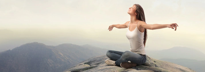 Chiropractic Anna TX Conditions Person sitting on a mountain with arms outstretched, suggesting relaxation.