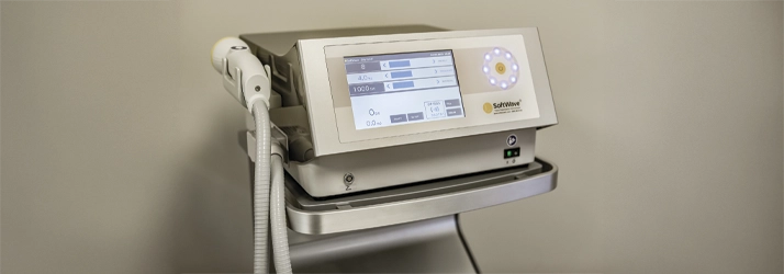 Chiropractic Anna TX Softwave A SoftWave medical device on a wheeled stand, featuring a digital display with settings and a handheld applicator connected by a flexible hose, used for therapeutic treatments.